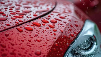 Close-up view of raindrops on a red vehicle.