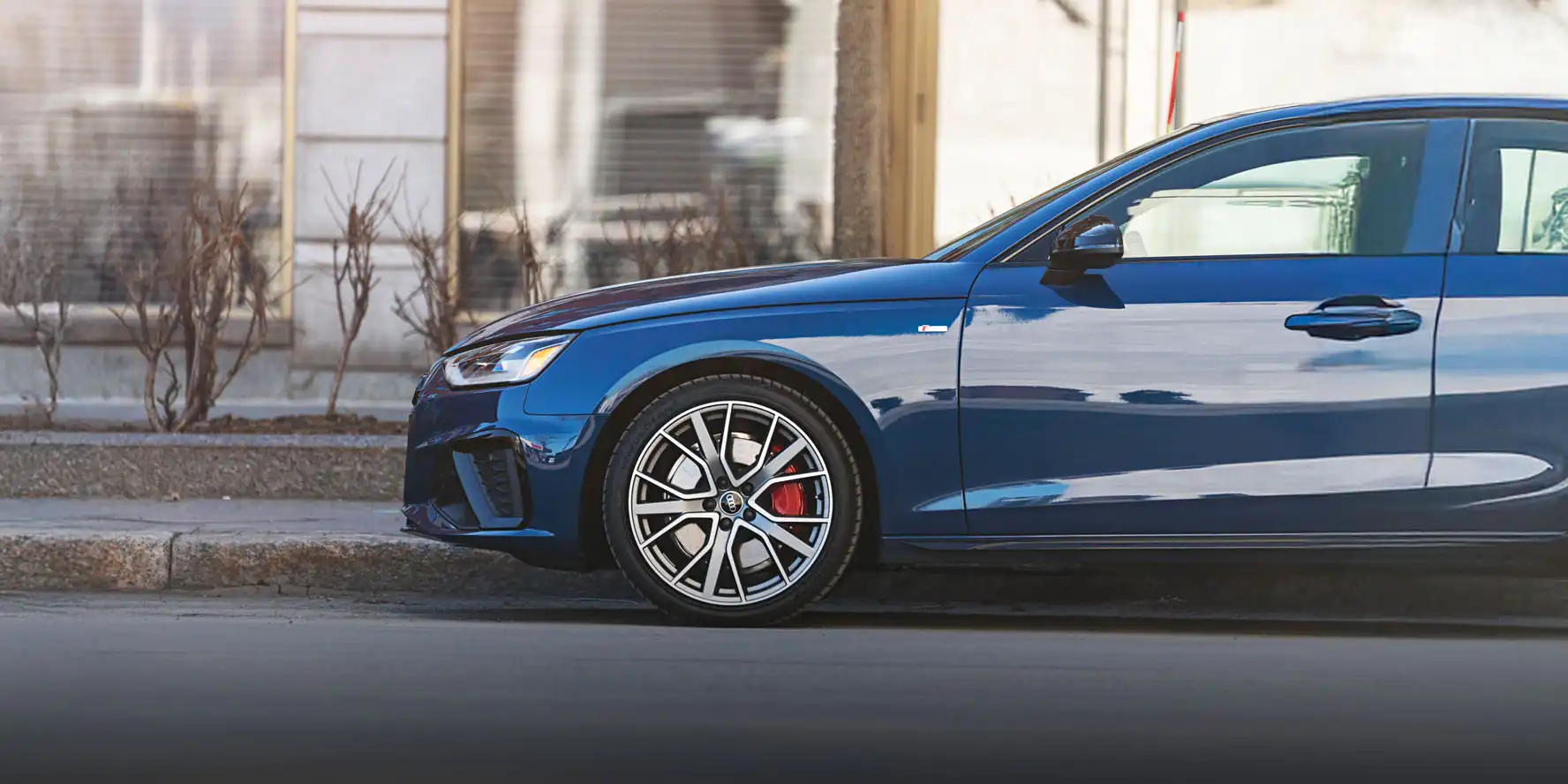 Vue de profil gauche de l'Audi A4 2024 de couleur bleue, stationnée en ville à Québec - Audi de Québec  