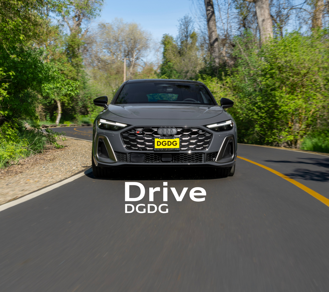 Front view of a grey Audi S5 sport sedan driving on a winding, tree-lined road.