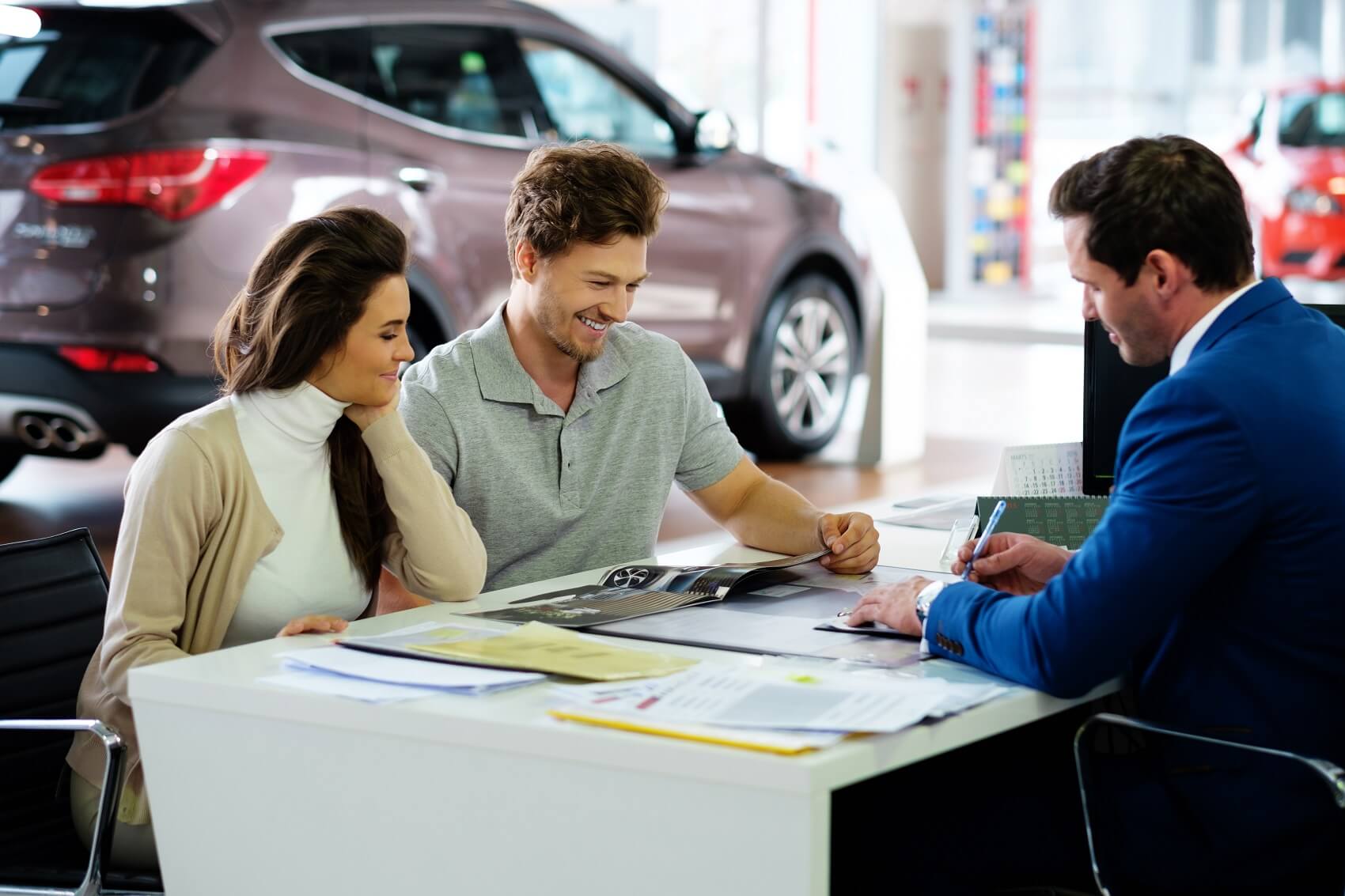 Couple sitting at desk at car dealership