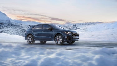 Side view of the Audi Q8 accelerating in a snowy landscape.