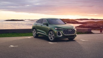 Three-quarter front view of the Audi Q5 Sportback parked by a waterfront.