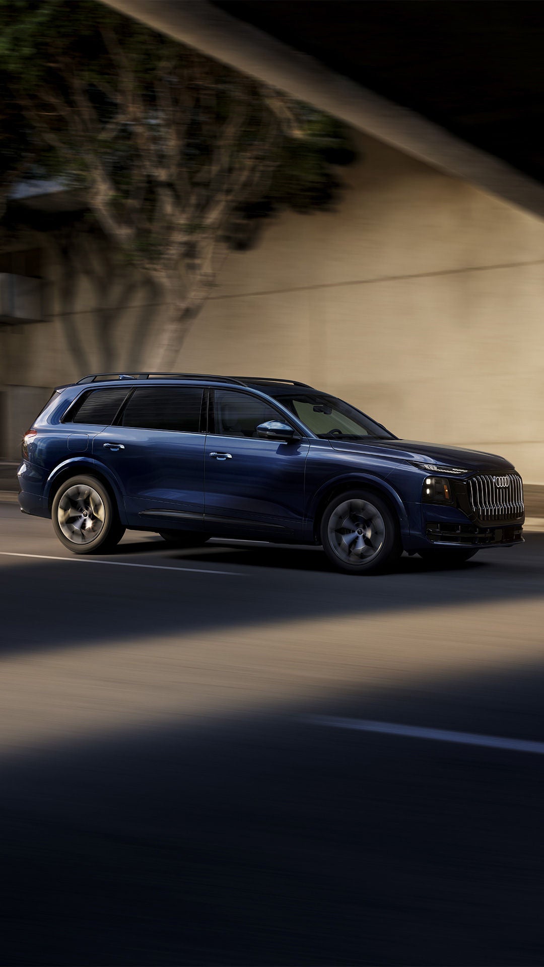 Side view of an Audi Q9 driving through the city.