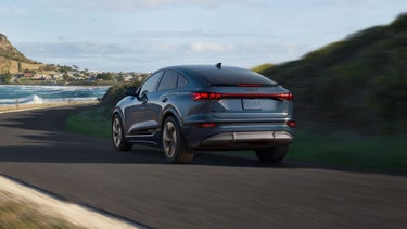 Three-quarter rear view of the Audi Q6 Sportback e-tron in front of a snowy mountainous landscape.