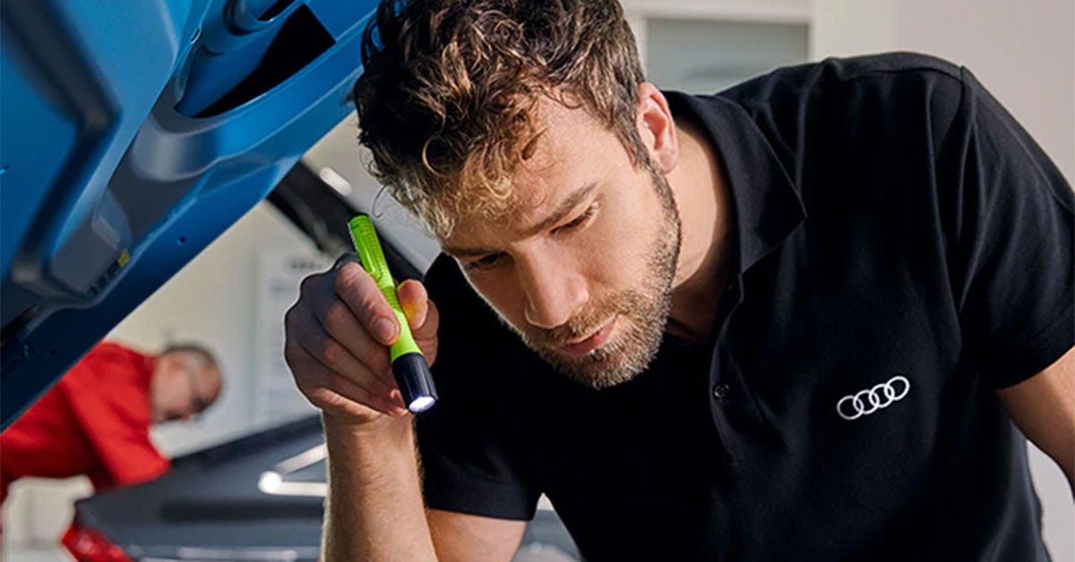 Technician inspecting vehicle at an Audi dealership
