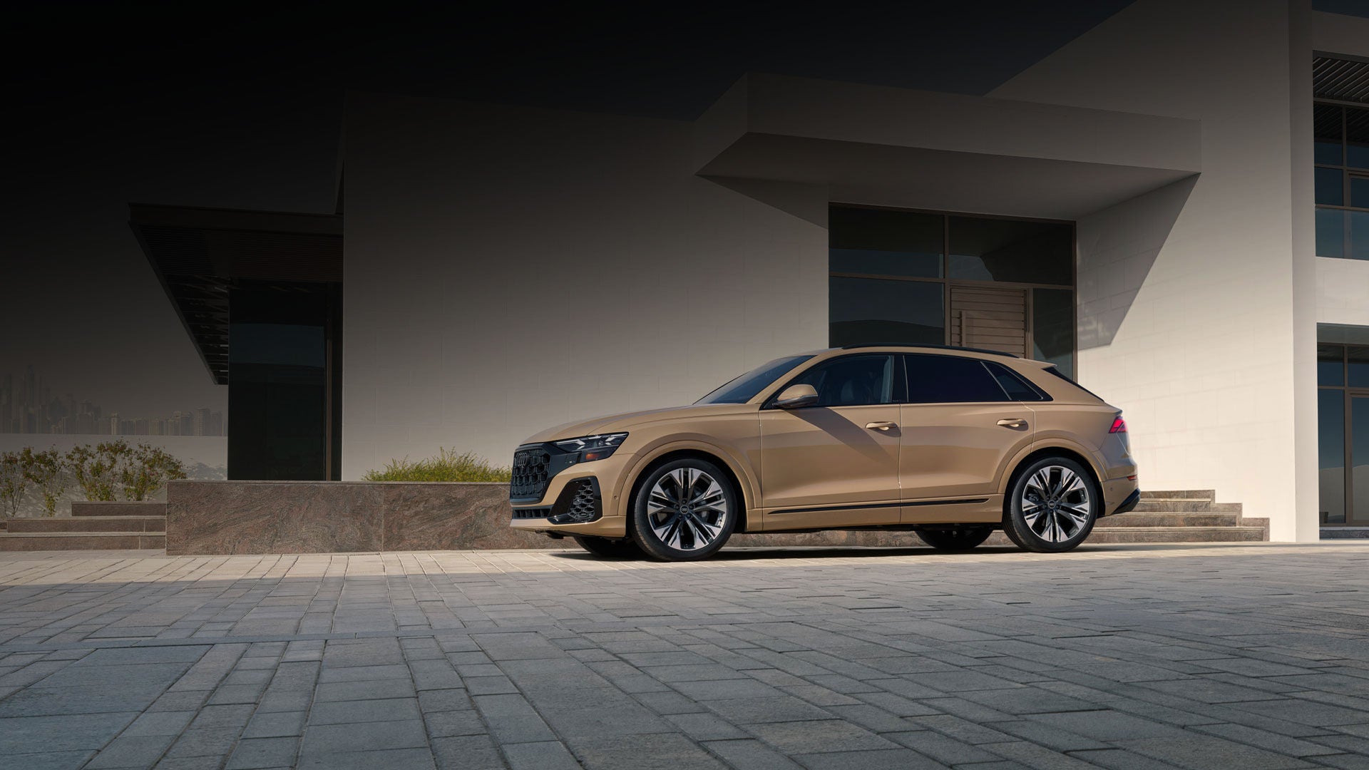Elevated side view of the Audi Q8 parked in front of a modern house.