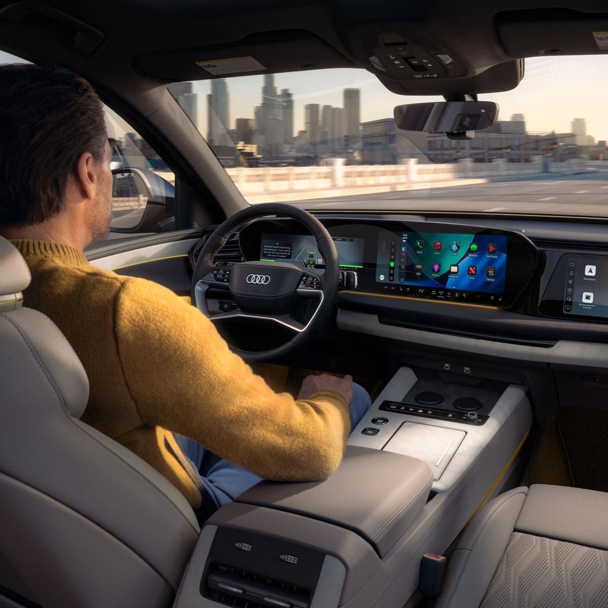 Close-up of a display in the vehicle interior. The silhouette of a vehicle travelling straight ahead is shown. To the left is a text box providing information about assisted hands-free driving.