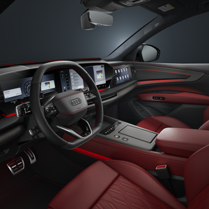 Look into the cockpit of the Audi SQ7 SUV with a black steering wheel, touchscreen, red leather interior, and red interaction lighting.
