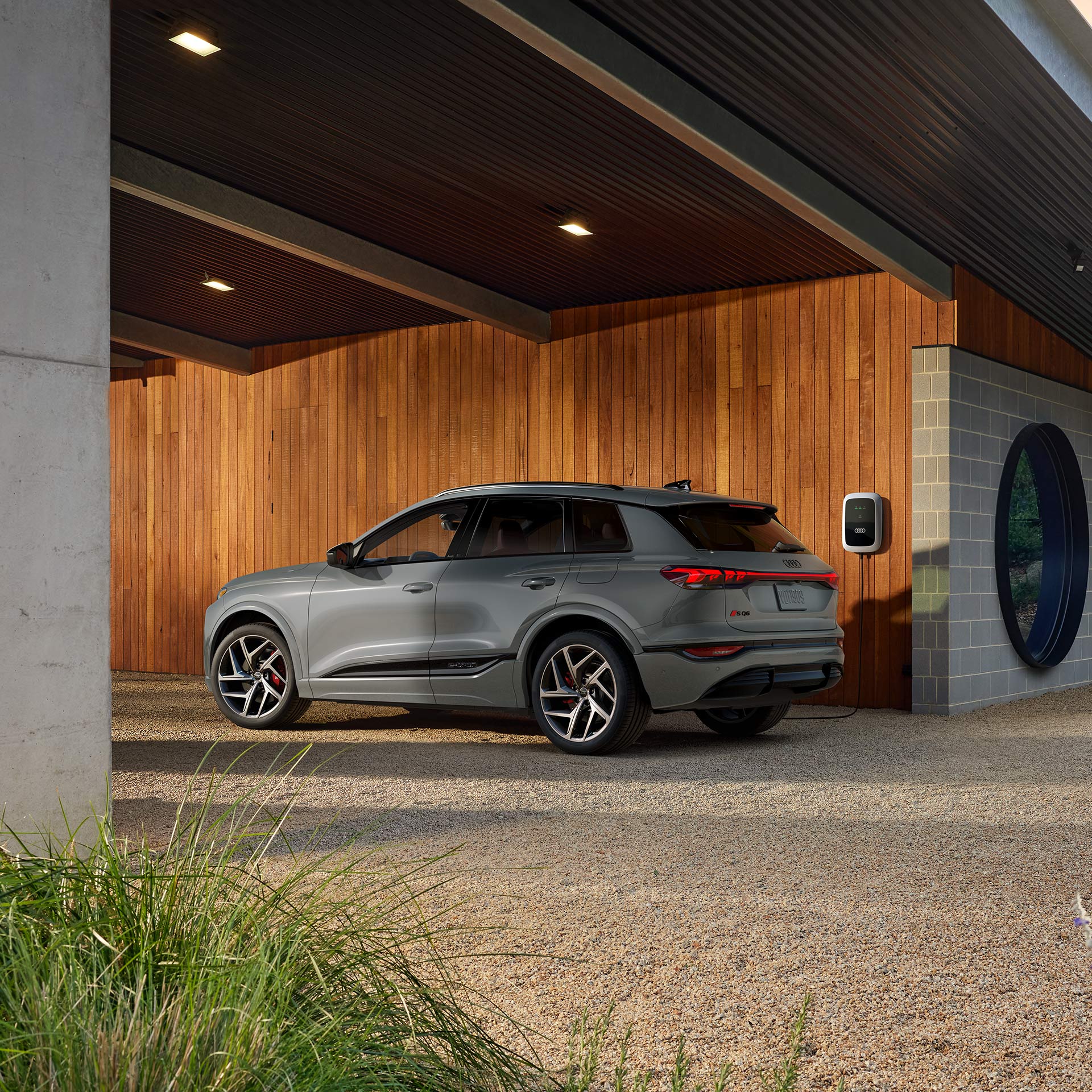 A man charging his Audi Q4 Sportback e-tron in front of a modern home.