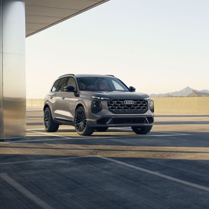 Three-quarter front view of the Audi SQ7 parked by a modern building.