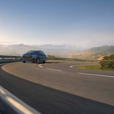2026 Audi Q8 in blue driving a mountain curve — V6 performance