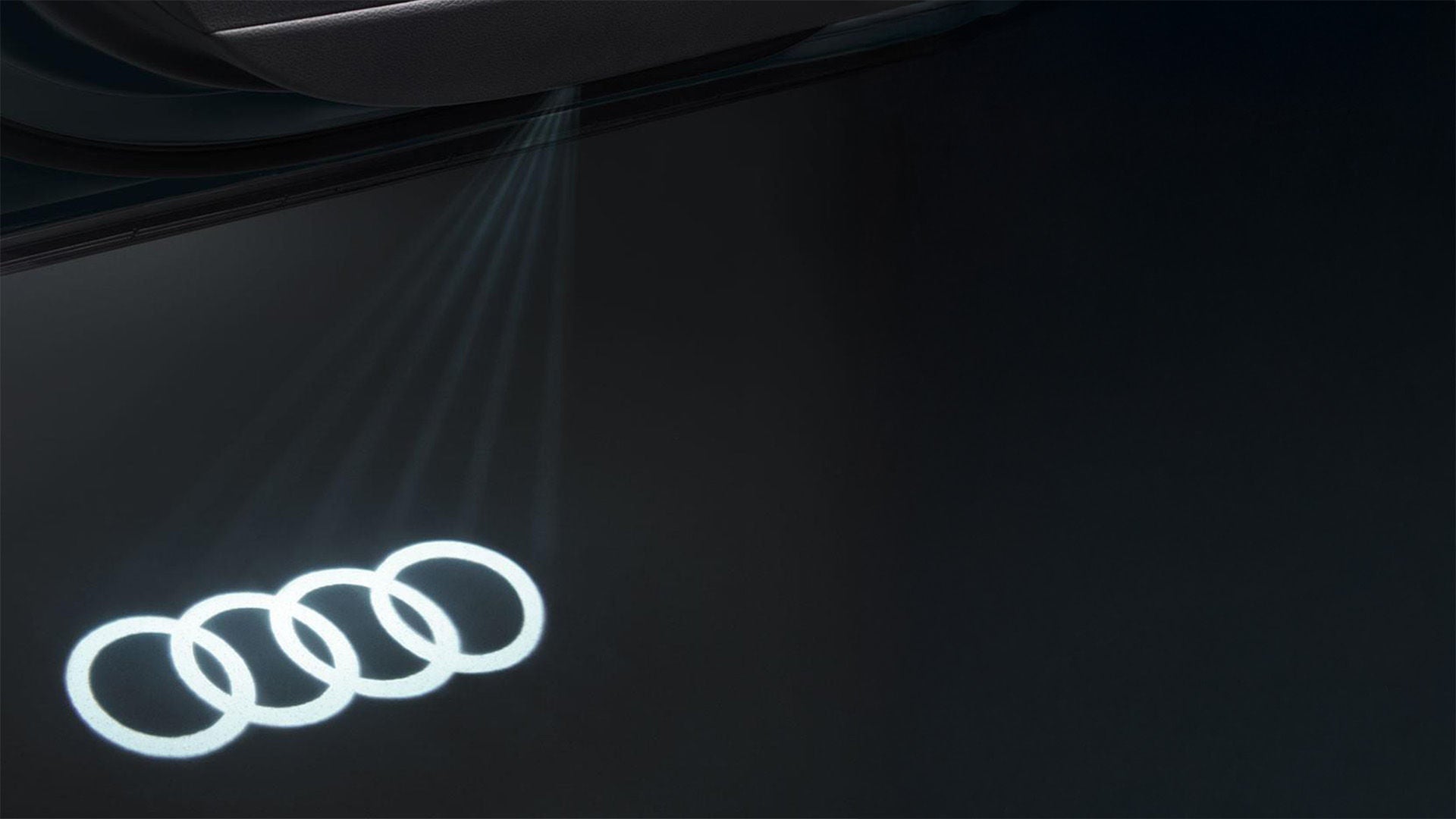 Audi rings being shone on a black background.