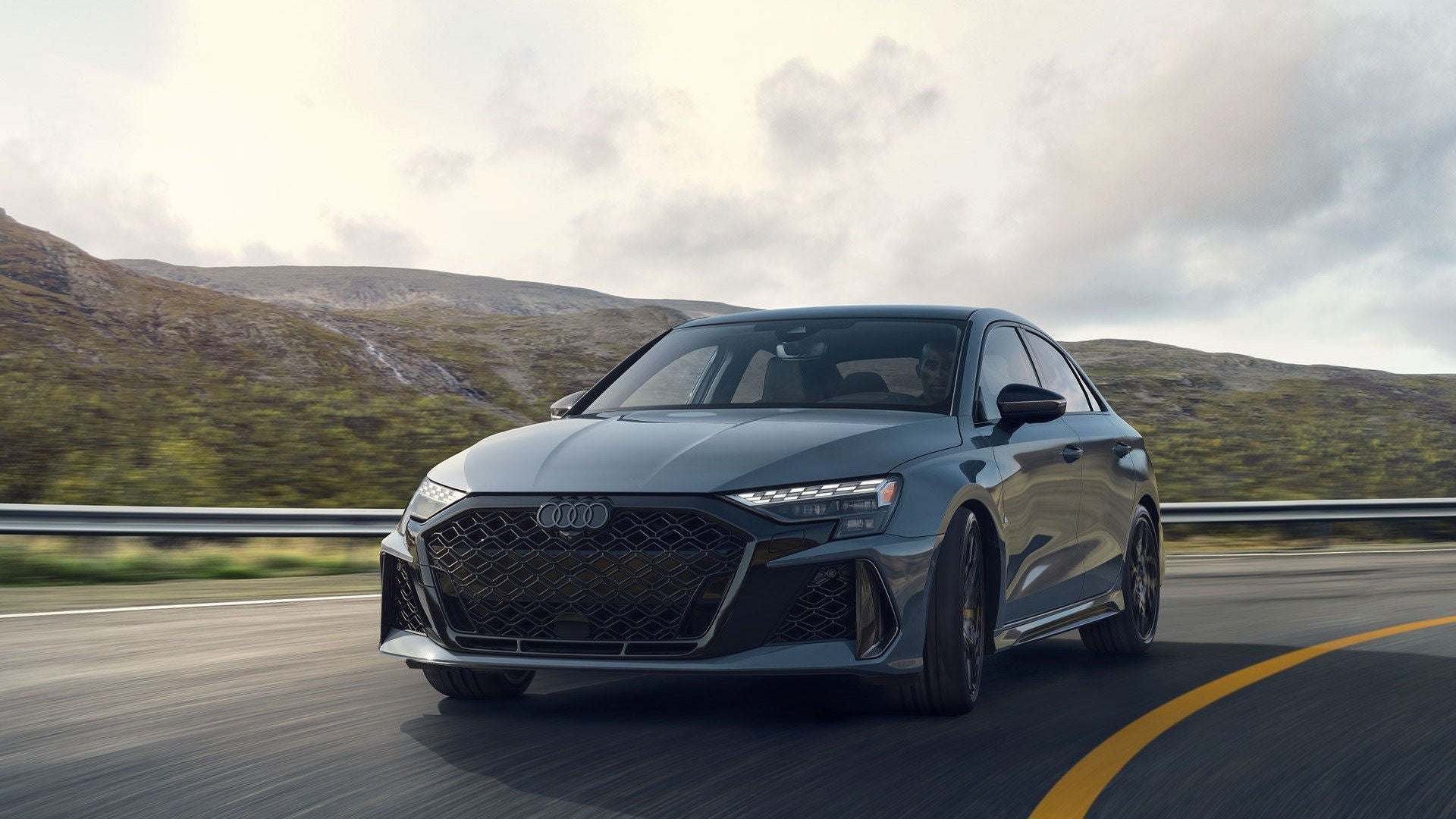 2026 Audi RS 3 driving, front three-quarter.