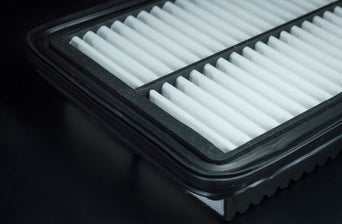 Service technician servicing vehicle with hood open.