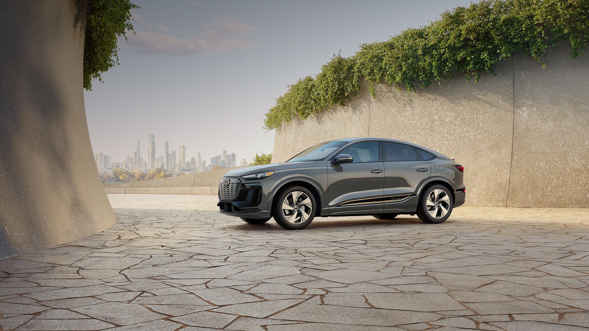 Three-quarter front profile of a gray Audi Q8 e-tron parked and charging on a driveway. 
