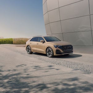Passenger side view of a beige Audi Q8 parked.