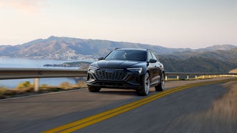 A black Audi Q8 e-tron driving on a mountain road. 