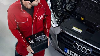 Service technician carrying a car battery. 
