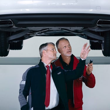 Two Audi Technicians inspecting the bottom of an Audi vehicle.