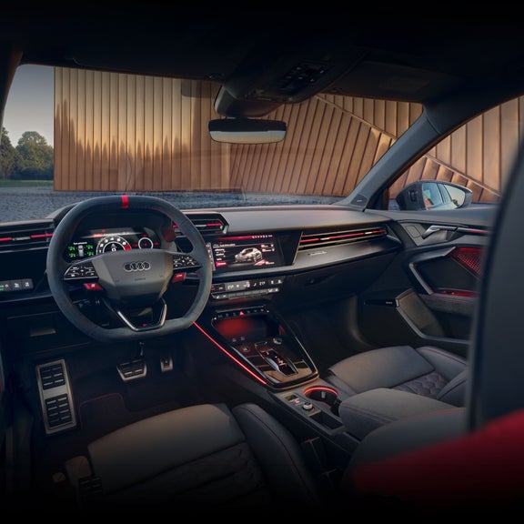 View of the interior cabin of the Audi RS 3, showing the virtual cockpit, steering wheels, and steel shift paddles.