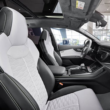 Interior shot of Audi RS Q8 with Silver and Black leather seating surfaces, Diamond Silver door trim inserts in Dinamica with Audi exclusive badges, and Black center and door armrests with Diamond Silver stitching.