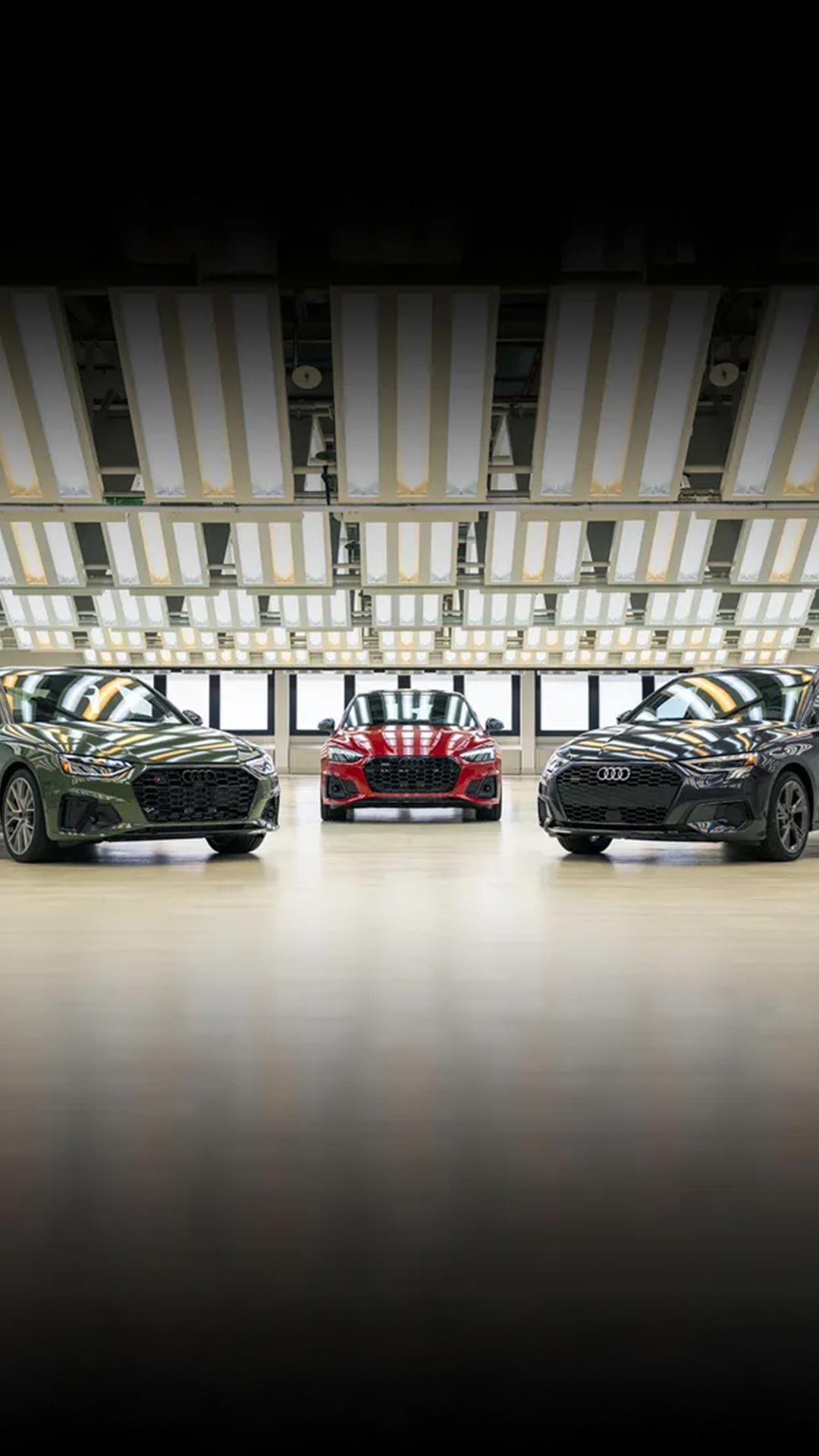 Three Audi cars parked side by side in a showroom-style garage