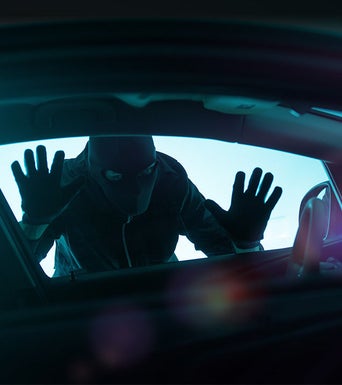 A masked and gloved person attempting to break into the vehicle.