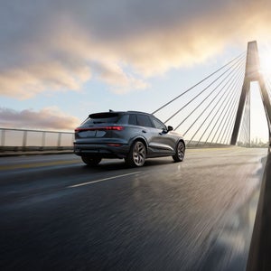 Three-quarter rear view of the Audi SQ6 e-tron accelerating on a large bridge.