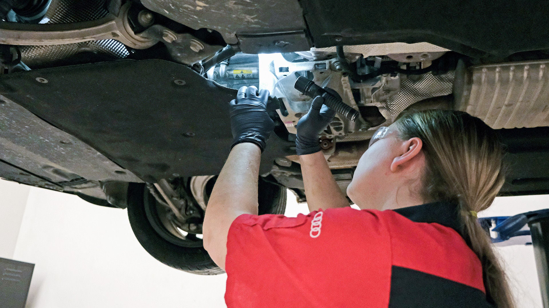 Audi service technician inspecting underneath car