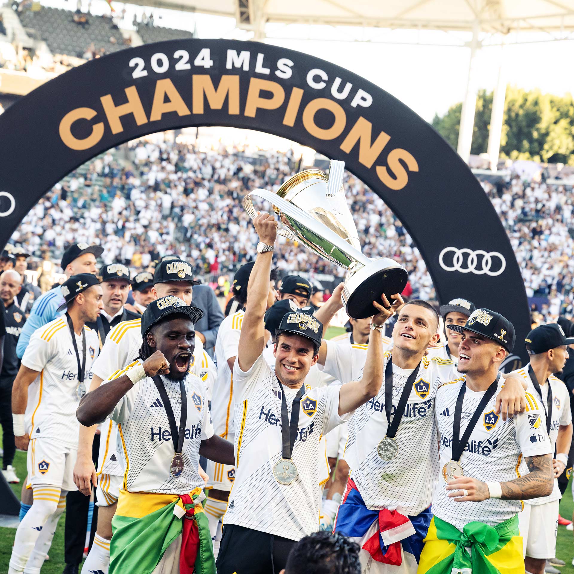 Soccer team taking a picture while celebrating win in stadium.