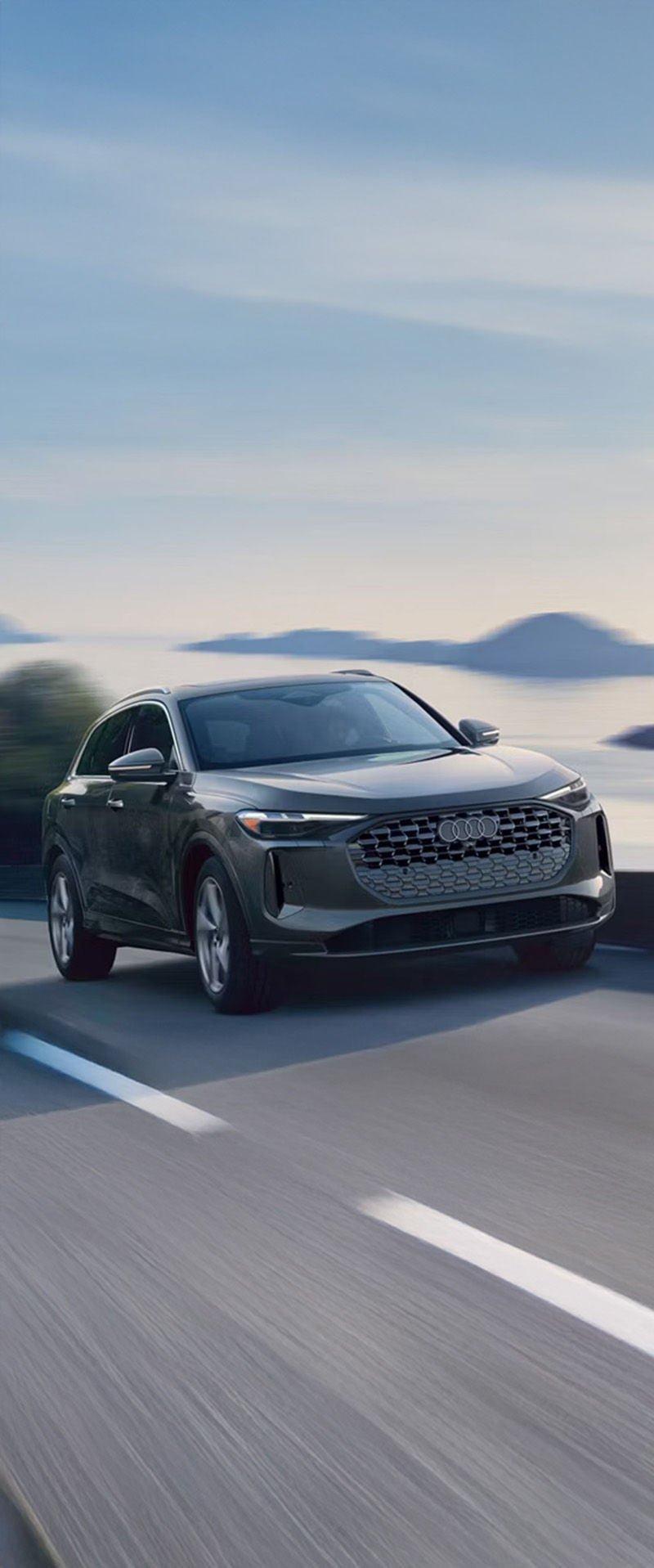 2025 Audi Q5 driving on mountain road with lake in background