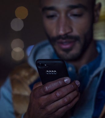 Close-up of a person using their smartphone with an Audi brand phone case.