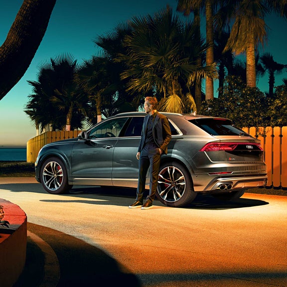 Three-quarter side view of the Audi SQ8 with person standing beside it.