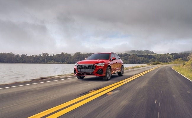 Audi Q3 driving on a highway by the water.