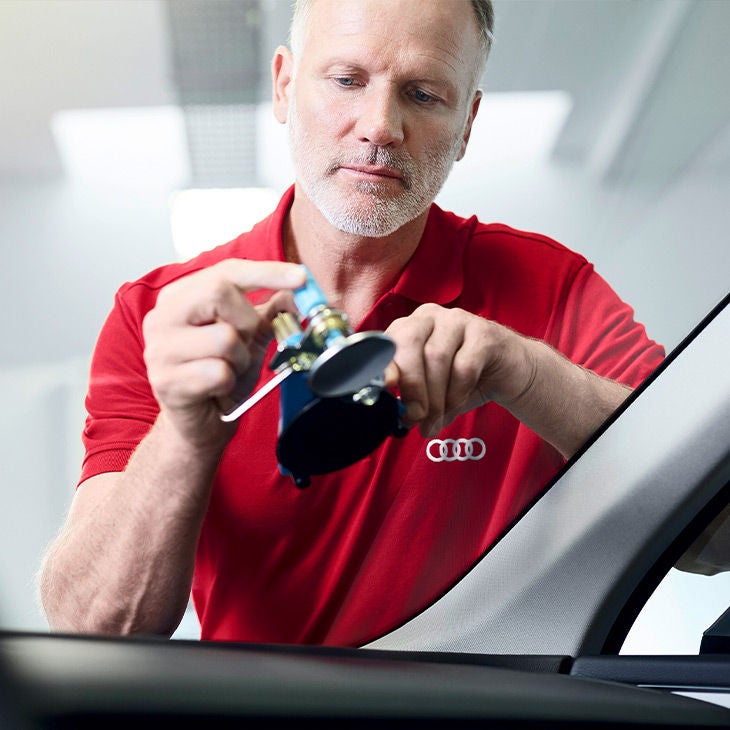 An Audi Technician inspecting a part on an Audi vehicle.