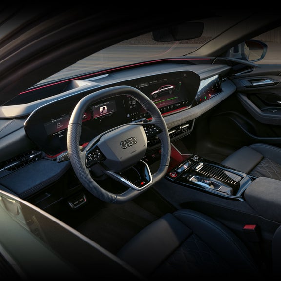 View of the interior cabin of the Audi S6 e-tron, showing the steering wheel, virtual cockpit, and centre console.