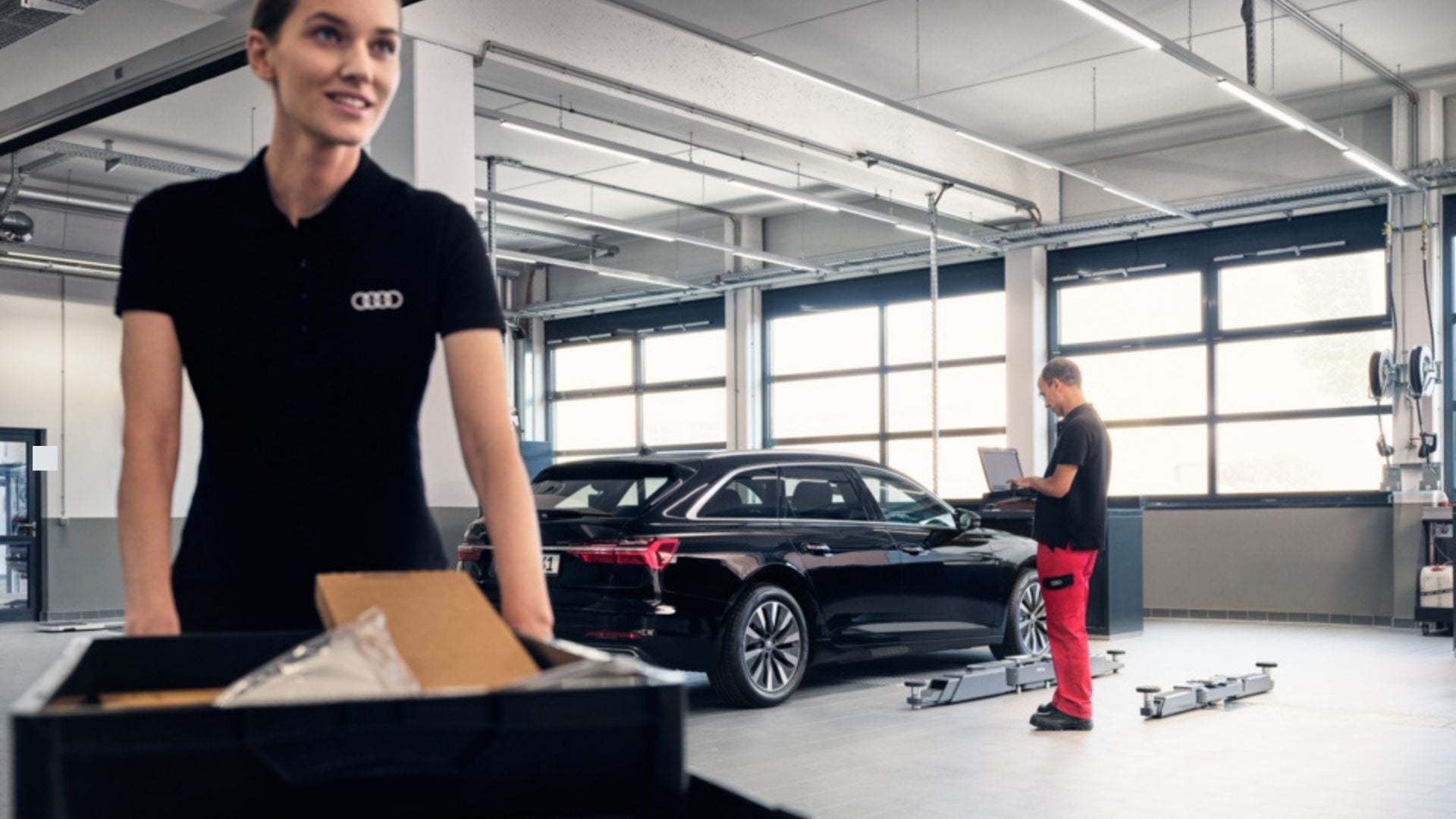 Woman pushing a parts cart while a tech works behind her