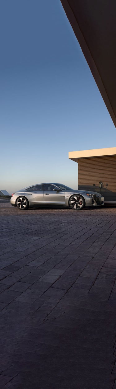 Side view of an Audi Q8 e-tron charging in front of a home.