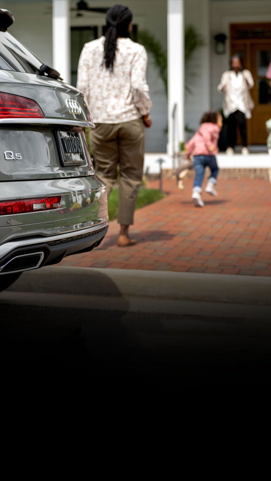 Family greeting outside their house with an Audi Q5 parked