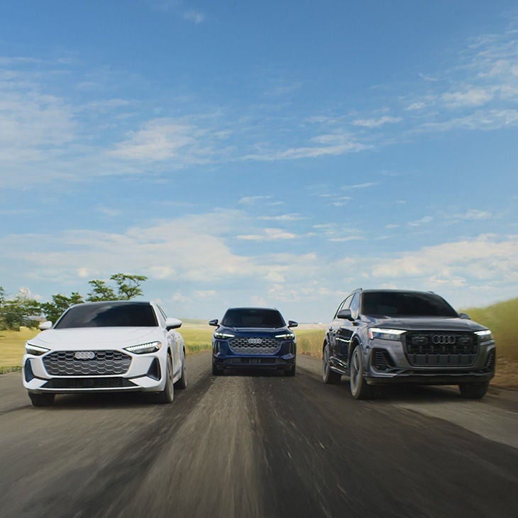 Front view of three Audi vehicles driving.