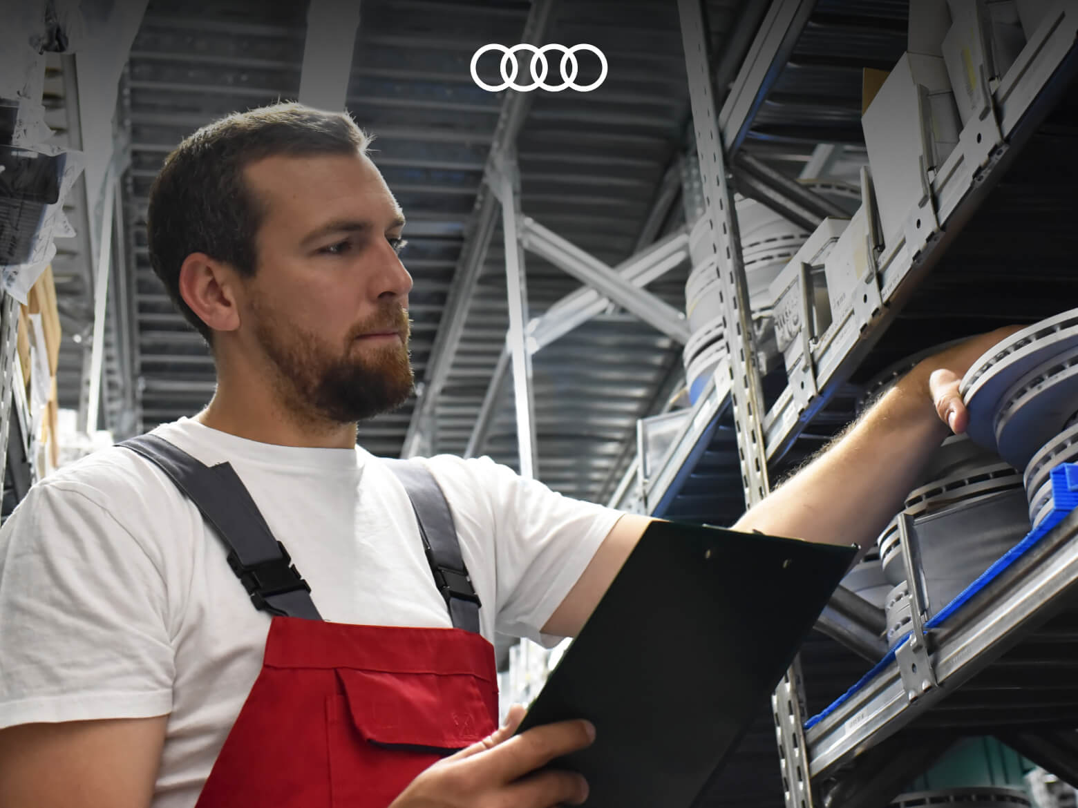 A low angle view of a man grabbing a brake rotor from a shelf of auto parts.