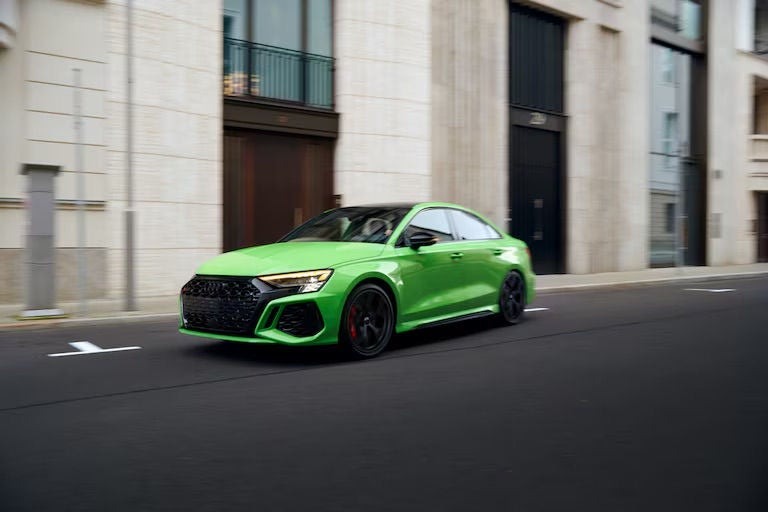 A bright green Audi sports sedan driving through a city street.