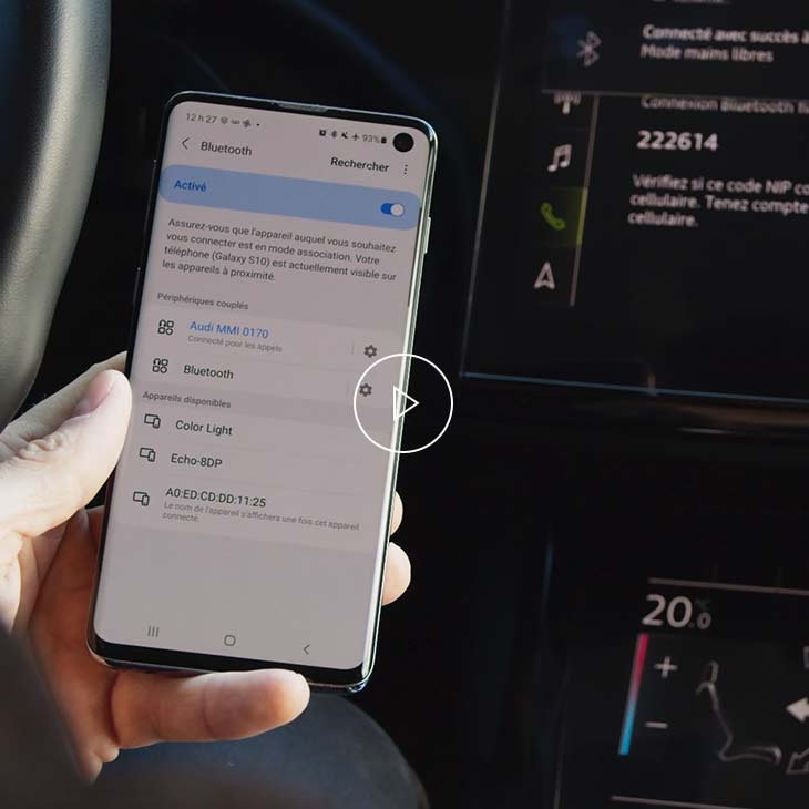 Gros plan d’une personne jumelant son téléphone cellulaire à son véhicule Audi par Bluetooth. 