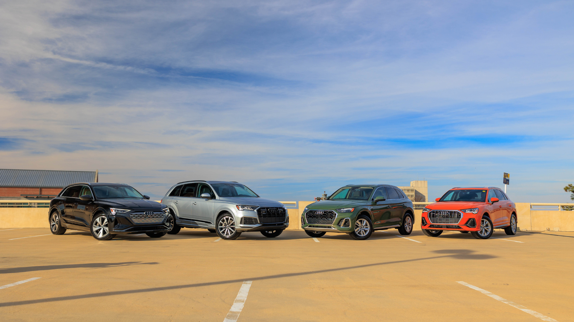 Lineup of 4 Audi SUVs parked with a blue sky in the background