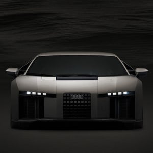 Front profile of the Audi Nuvolari in a darkened room with the headlights lit up.