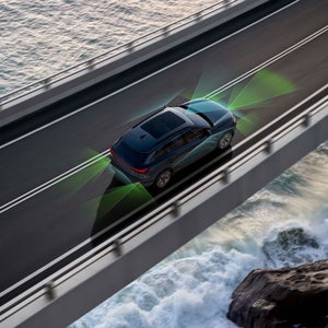 Aerial view of the Audi SQ6 e-tron accelerating on a bridge over water, with illustrations demonstrating the adaptive cruise assist feature.