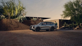 Three-quarter front view of the Audi SQ7 parked on a driveway with a person opening up the trunk.
