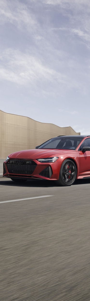 Three-quarter front view of the Audi RS 6 Avant accelerating on a city road.