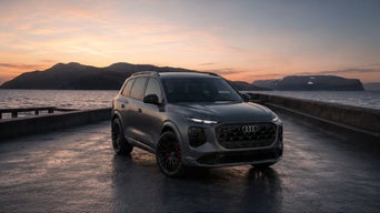 Three-quarter front view of the Audi SQ9 parked by a waterfront.