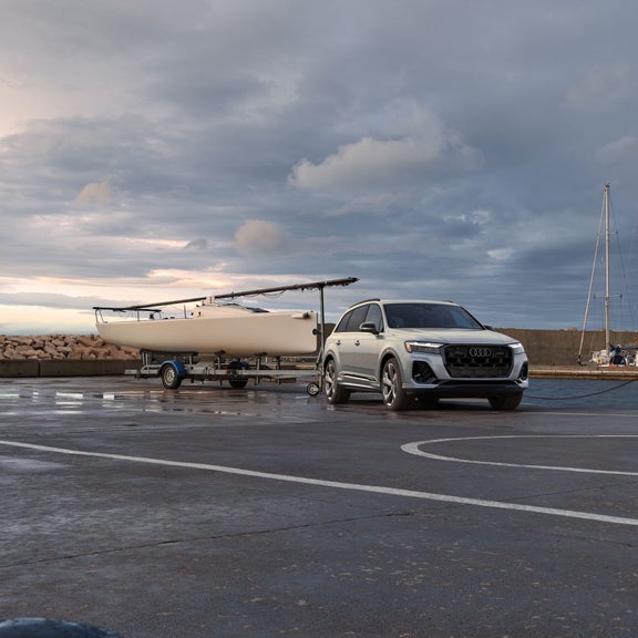 Front 3/4 profile of the Audi Q7 with a boat attached to its hitch. 